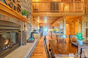 Clayton house for rent - A large wooden dining table is surrounded by chairs in a spacious room with a stone fireplace.
