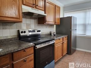 Manassas apartment for rent - A kitchen with wooden cabinets and black appliances.