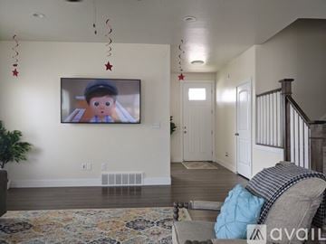 Eagle Mountain house for rent - A living room with a television mounted on the wall and a couch with a blue pillow in front of it.