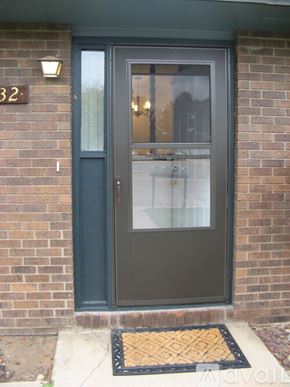 Longmont apartment for rent - A grey door with a glass window and a black mat in front of it.