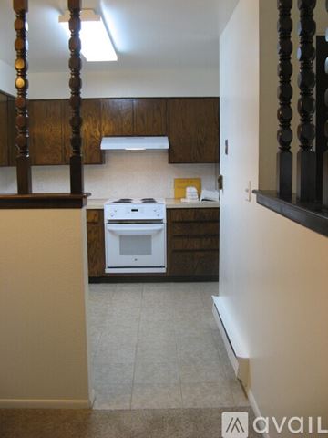 Longmont apartment for rent - A kitchen with a white stove top oven and wooden cabinets.