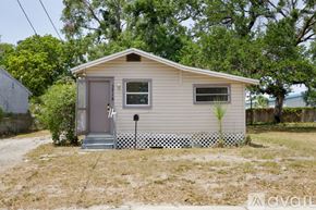 St. Petersburg house for rent - A small house with a grey door and a window is surrounded by a white picket fence.