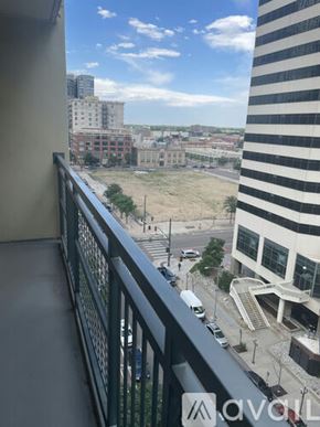 Denver apartment for rent - A balcony overlooks a city street with cars and buildings.