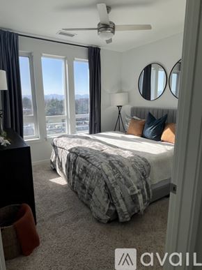 Denver apartment for rent - A bedroom with a large bed and a view of the outdoors through the windows.
