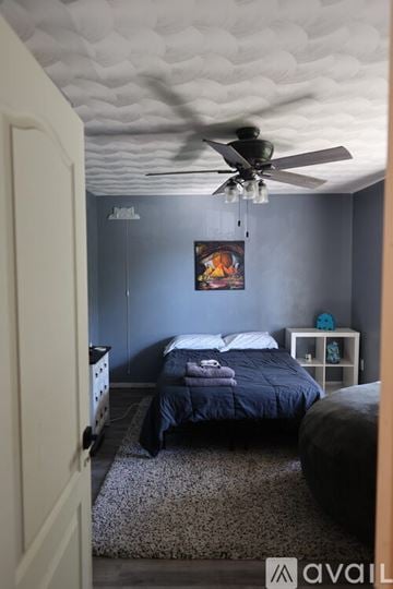 Norfolk house for rent - A bedroom with a bed, a ceiling fan, and a painting on the wall.