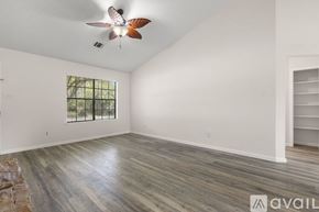 Round Rock house for rent - A spacious room with a ceiling fan and wooden flooring.