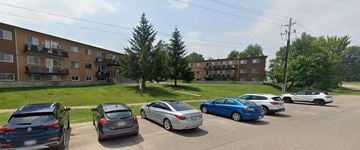 Deep River apartment for rent - A parking lot with cars and apartment buildings in the background.