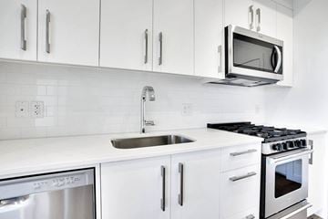 Calgary house for rent - A modern kitchen with white cabinets and stainless steel appliances.