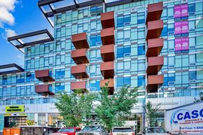 Calgary house for rent - A modern building with a glass facade and red balconies.