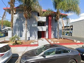 Redwood City apartment for rent - A grey car is parked in front of a building with a red awning.
