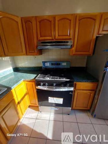 Jersey City apartment for rent - A kitchen with wooden cabinets and a black stove top oven.