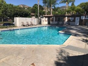 San Diego condo for rent - A large outdoor swimming pool surrounded by a concrete patio and a small building.