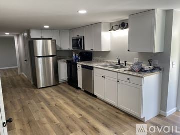 Rose Hill townhouse for rent - A kitchen with white cabinets and a wooden floor.