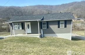 Rose Hill townhouse for rent - A small house with a grey roof and a white door is surrounded by a grassy area.