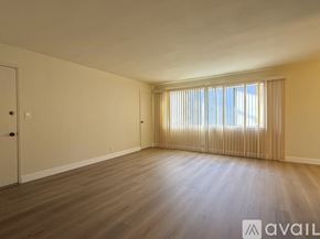 Long Beach apartment for rent - A spacious room with wooden flooring and a window with blinds.