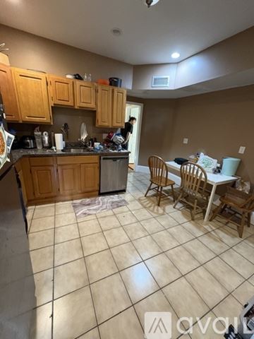 Boston apartment for rent - A kitchen with wooden cabinets and a person standing in the doorway.