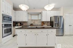 Plano house for rent - A kitchen with white cabinets and a marble countertop.