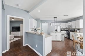 Lewisville house for rent - A kitchen with white cabinets and a blue island.