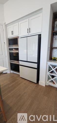 Justin house for rent - A kitchen with white cabinets and a black fridge.