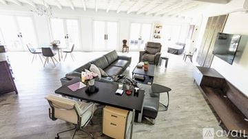 San Diego house for rent - A living room with a black sofa and a black coffee table with a vase of flowers on it.