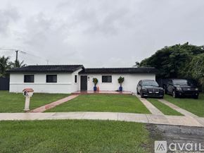 Miami house for rent - A white house with a red roof and a black car parked in front.
