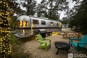 Cat Spring apartment for rent - A silver RV is parked in a gravel lot next to a picnic table and chairs.