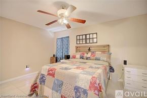 Sebring house for rent - A bedroom with a bed, a ceiling fan, and a window with curtains.
