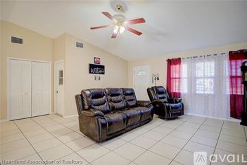 Sebring house for rent - A living room with a black leather couch and a fan on the ceiling.
