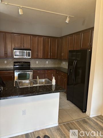 Englewood condo for rent - A kitchen with wooden cabinets and a black fridge.