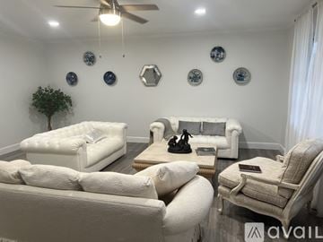 Palm Beach Gardens house for rent - A living room with white furniture and decorations on the wall.