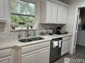 Palm Beach Gardens house for rent - A kitchen with white cabinets and a black dishwasher.