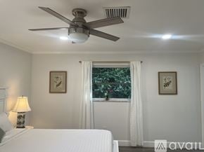 Palm Beach Gardens house for rent - A bedroom with a white bed and a ceiling fan.