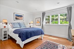 Norwalk house for rent - A bedroom with a large bed and a window with curtains.