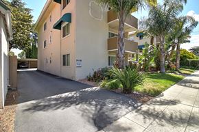 San Mateo apartment for rent - a beige apartment building with a driveway and palm trees