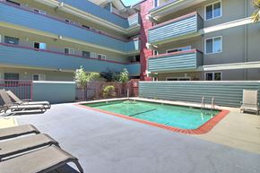 Belmont apartment for rent - A pool surrounded by chairs and apartment buildings.