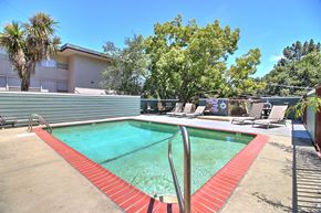 Belmont apartment for rent - A pool with red poolside chairs and a metal ladder.
