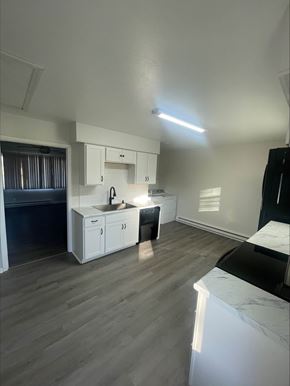 Lima apartment for rent - A kitchen with white cabinets and a black countertop.
