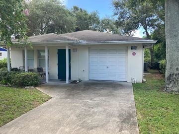 Clearwater apartment for rent - A small white house with a blue door and a garage door.