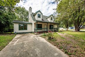 Jacksonville house for rent - A house with a green lawn and trees in the background.