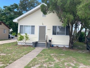 Clearwater house for rent - A small house with a grey door and a tree in front.