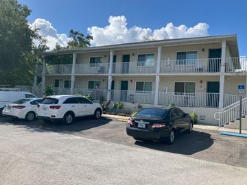 Clearwater apartment for rent - A black car is parked in front of a white building with a balcony.