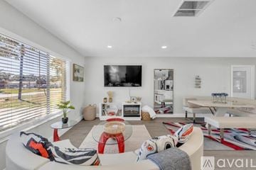 Palm Coast house for rent - A living room with a white couch and a flat screen TV mounted on the wall.