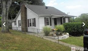 Knoxville house for rent - A white house with a grey roof and a black fence.