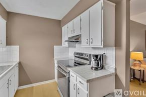Newburgh apartment for rent - A kitchen with white cabinets and appliances, a countertop, and a small table with a lamp.