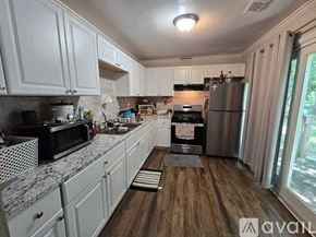 Charlotte house for rent - A kitchen with white cabinets and a wooden floor.