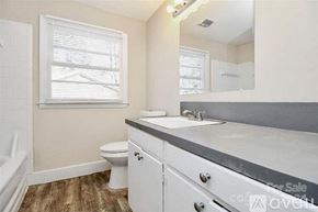 Charlotte house for rent - A bathroom with a toilet, sink, and mirror.