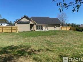 Albany house for rent - A house with a grey roof and a brown fence is surrounded by a grassy area.