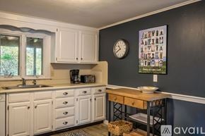Sandwich house for rent - A kitchen with white cabinets and a wooden table.
