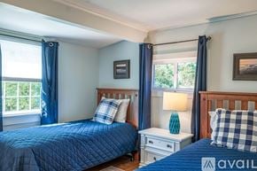 Sandwich house for rent - A bedroom with a blue bedspread and a white nightstand with a lamp.
