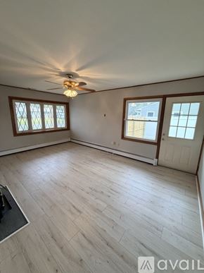 Levittown house for rent - A room with a ceiling fan and light, hardwood floors, and two windows.